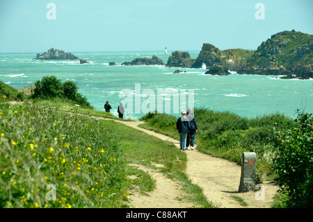 Un giovane sta camminando sul punto di Grouin, vista dell'isola di Landes (Brittany, Francia). Foto Stock