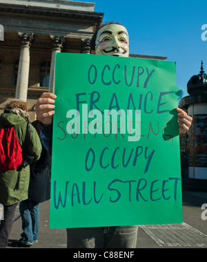 Parigi, Francia, Man in Mask Holding Sign outside Paris Bourse, 'Occupy France', protestando l'avidità aziendale e le politiche di austerità del governo. Dimostrazione, sostegno internazionale del segno di protesta 'Occupy Wall Street', giovani che protestano contro lo stock, Anti capitalismo Foto Stock