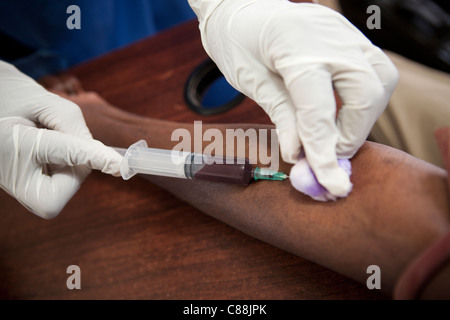 Un infermiere aspira il sangue da un HIV positiva paziente presso una clinica supportata da Catholic Relief Services a Kitwe, Zambia. Foto Stock