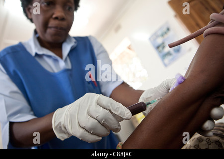 Un infermiere aspira il sangue da un HIV positiva paziente presso una clinica supportata da Catholic Relief Services a Kitwe, Zambia. Foto Stock