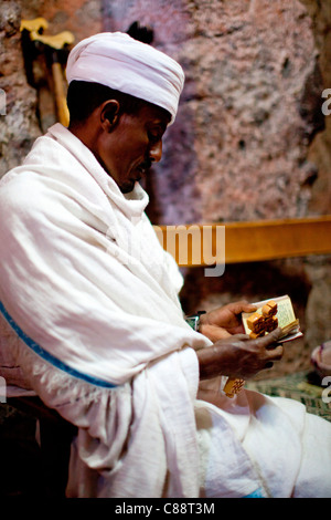 Un cristiano ortodosso sacerdote legge preghiere accanto alla tomba di Re Lalibela in rock-scavato nella chiesa di scommettere sul Golgota in Lalibela. Foto Stock