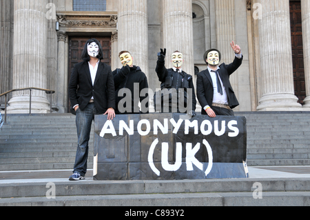 Anonimo UK manifestanti indossando Guy Fawkes maschere anti capitalisti creare una tenda nella città di San Paolo cortile vicino al London Stock Exchange nel secondo giorno di occupare di Londra. Domenica 16 Ottobre 2011 Foto Stock