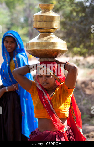 Donna indiana portando vasi d'acqua sul suo capo a Sawai Madhopur nel Rajasthan, India settentrionale Foto Stock