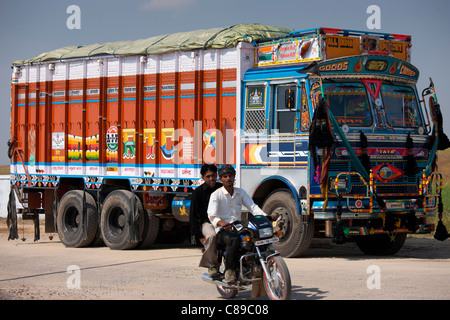 Indian motociclista passa di Tata camion a Rasulpura in Sawai Madhopur, Rajasthan, India settentrionale Foto Stock