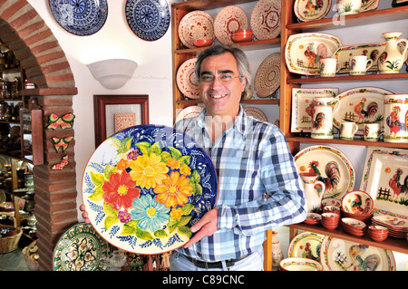 Portogallo Alentejo: proprietario di un negozio di Amilcar mostra raditional piastra ceramica nel suo negozio di souvenir 'Mufla' in Monsaraz Foto Stock
