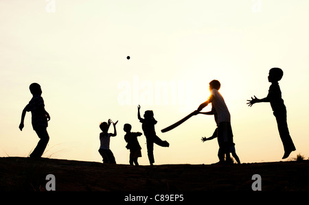 Silhouette di giovani indiani ragazzi giocare a cricket francese al tramonto in India Foto Stock