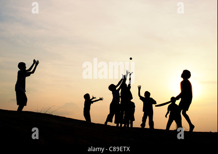 Silhouette di giovani indiani ragazzi giocare a cricket francese al tramonto in India Foto Stock