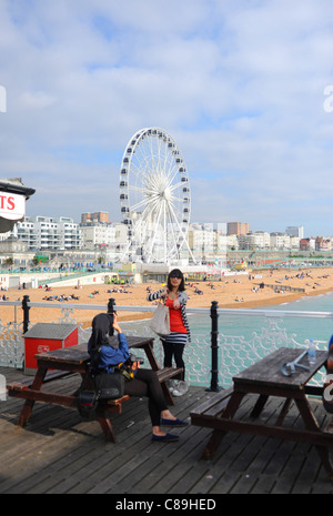 I visitatori di prendere foto di se stessi sul molo di Brighton con la ruota di eccellenza in background sul lungomare Foto Stock