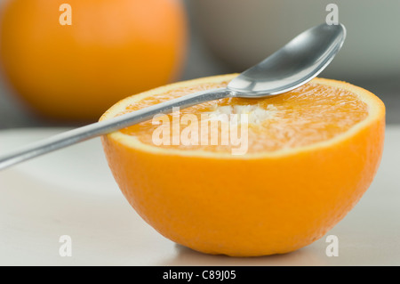 Mezzo taglio arancione con cucchiaio sulla parte superiore di esso, close up Foto Stock