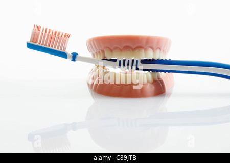 Protesi a base di zucchero e cioccolato bianco con spazzolino da denti su sfondo bianco, close up Foto Stock