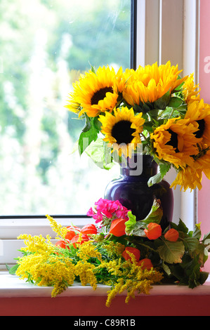 Un vaso di tarda estate fiori su un davanzale, compresi i girasoli e golden asta REGNO UNITO Foto Stock