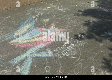 Bambino disegno gesso sul marciapiede o percorso nel parco giochi per bambini Foto Stock