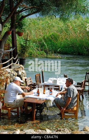 AKYAKA, Turchia. Due uomini di bere birra dal / al fiume Azmak, con la conservazione di Gokova area dietro. 2011. Foto Stock