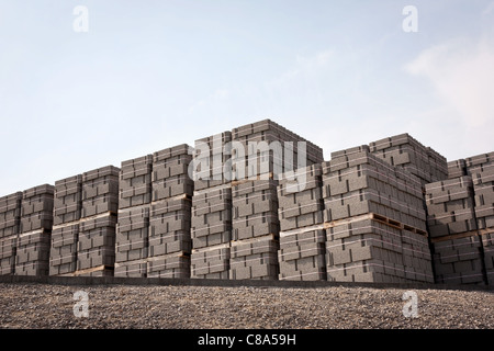 I pallet di nuovi blocchi di cemento sotto la luce del sole contro il cielo blu Foto Stock