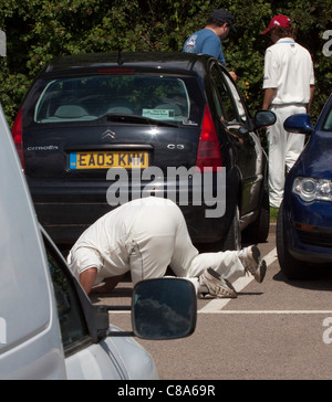 La ricerca di una palla persa nel parcheggio in un villaggio di partita di cricket. Foto Stock