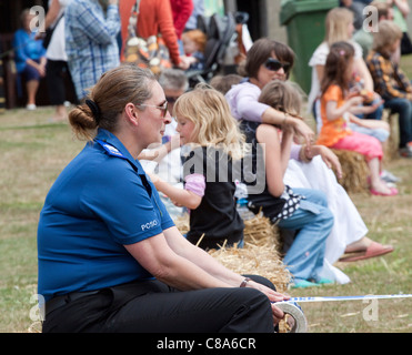 Una femmina di comunità di polizia funzionario di supporto mantiene il nastro per una gara a un divertimento per tutta la famiglia al giorno. Foto Stock