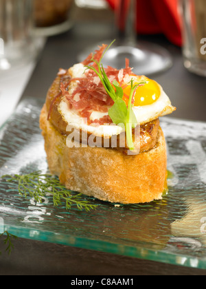 Prosciutto Spagnolo,il foie gras e quaglie di un uovo di sandwich aperto Foto Stock