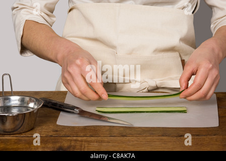 Cuocere la preparazione di fette di cetriolo per makis Foto Stock
