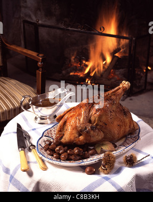 Il cappone con castagne, su tavola con caminetto Foto Stock