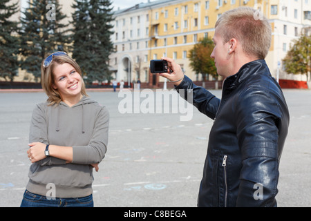 Uomo di fotografare giovane bella donna contro le attrazioni della citta'. Estate, all'esterno. Amare giovane in Russia Foto Stock