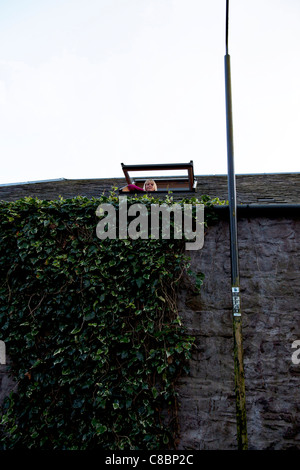 Gartmore, Scozia, lady guardando fuori di una inclinazione velux finestra sul tetto dorma finestra aperta inclinato verso l'alto Foto Stock