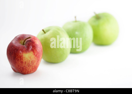 Un rosso Apple si distingue da una folla di mele verdi. Isolato su uno sfondo bianco. Foto Stock