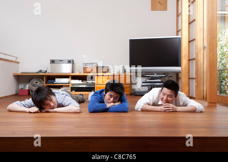 Tre uomini relax su pavimento in legno duro Foto Stock