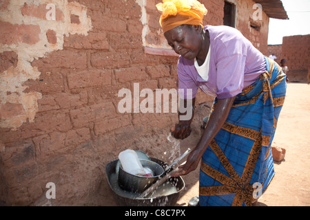 Una donna lava le mani al di fuori di casa sua in Mongu, Zambia, Sud Africa. Foto Stock