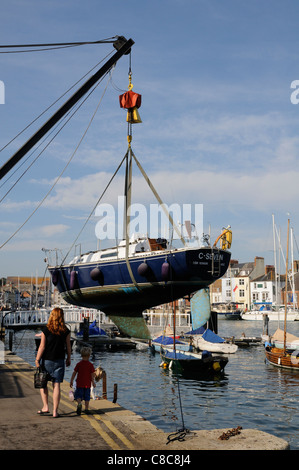 Barca a vela che viene sollevato dall'acqua per la pulizia del porto di Weymouth Dorset England Regno Unito Foto Stock