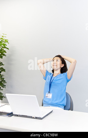 Metà donna adulta in business casual cercando fino alla scrivania Foto Stock