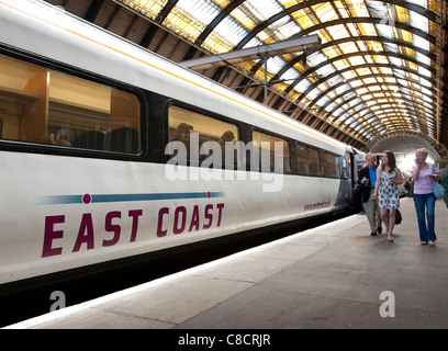 Passeggeri a camminare al fianco di un treno ad alta velocità nella costa est livrea treni presso la stazione di Kings Cross a Londra, Inghilterra. Foto Stock