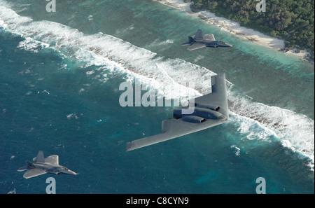 Due F-22 rapaci e un B-2 bombardiere spirito dispiegato per Andersen Air Force Base, Guam, volare in formazione sull'Oceano Pacifico. Foto Stock