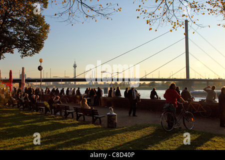 La passeggiata sul fiume lungo il fiume Reno. La gente seduta e camminare lungo le rive del fiume e la città vecchia di Düsseldorf, Germania. Foto Stock