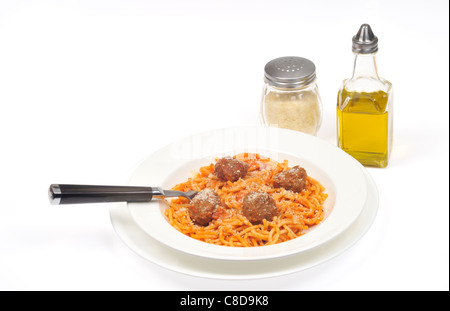 Una porzione di spaghetti e polpette di carne conditi con formaggio in una ciotola bianca con cucchiaio su sfondo bianco. Foto Stock