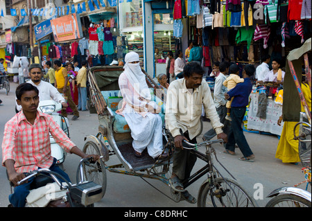 Scena di strada nella città santa di Varanasi, giovane donna musulmana in bianco corse burkha in rickshaw, Benares, India settentrionale Foto Stock