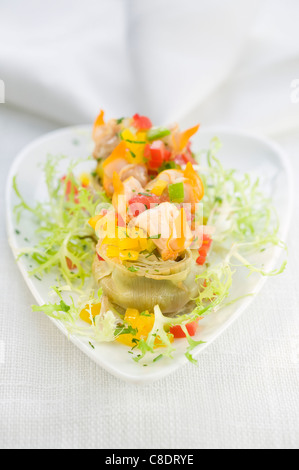 Cuori di carciofi farciti con frutti di mare e tre peperoni colorati Foto Stock