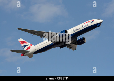 British Airways Boeing 777-200 ER widebody jet del passeggero salendo sulla partenza contro un cielo blu Foto Stock