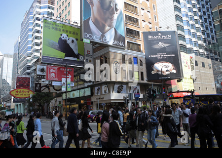 Occupato strada dello shopping di Kowloon, Hong Kong, Cina, decine di cross al semaforo sotto i cartelloni per high end beni di marca Foto Stock