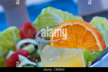 Sana vacanza alfresco pasto a base di insalata mista e succo di arancia sulla terrazza a bordo piscina. Foto Stock