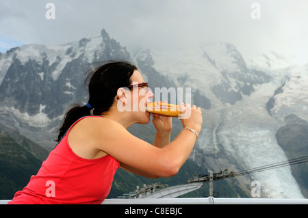 Una donna prendendo un grosso morso al di fuori di un enorme panino Foto Stock