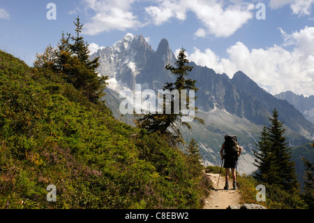 Un camminatore su un sentiero nelle Alpi francesi con l'Aiguille Verte e les Drus oltre Foto Stock
