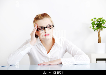 Donna di mezza età seduta dietro la scrivania in ufficio avente mal di testa. Foto Stock