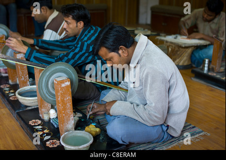 Abili artigiani al lavoro rendendo la pietra dura souvenir usando il tradizionale vecchia mola in Agra, India Foto Stock