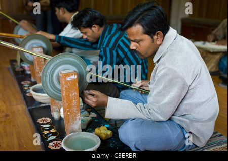 Abili artigiani al lavoro rendendo la pietra dura souvenir usando il tradizionale vecchia mola in Agra, India Foto Stock