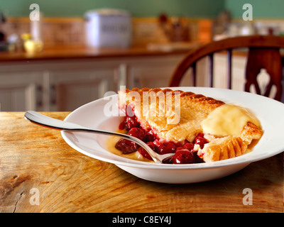 Britannico tradizionale torta di ciliegie e crema pasticcera budino servito caldo in un recipiente in una impostazione di cucina Foto Stock