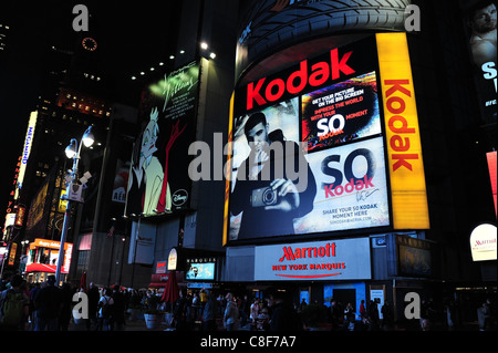 Notte tempo-shot folla di persone a piedi sotto il neon Disney Kodak cartelloni facciata Marriott Hotel, Broadway e Times Square, New York Foto Stock