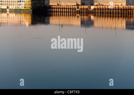 Riflessioni in golden acqua in mattina presto luce ridondante di navi da crociera ormeggiate vicino edifici industriali sul Nilo Foto Stock