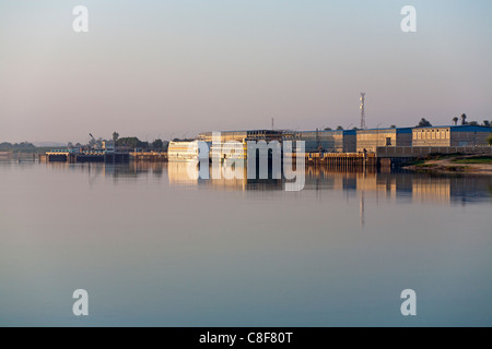 Crociera ridondanti le navi ormeggiate nei pressi di edifici industriali sul Nilo riflettente nel golden acqua in mattina presto luce, Egitto Foto Stock