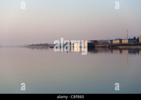 Crociera ridondanti le navi ormeggiate nei pressi di edifici industriali sul Nilo riflettente nel golden acqua in mattina presto luce, Egitto Foto Stock