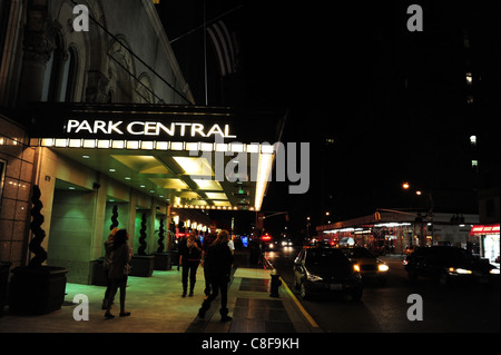 Visione notturna illuminata tettoia ingresso Park Central Hotel, marciapiede persone, fari traffico, 7th Avenue, New York Foto Stock